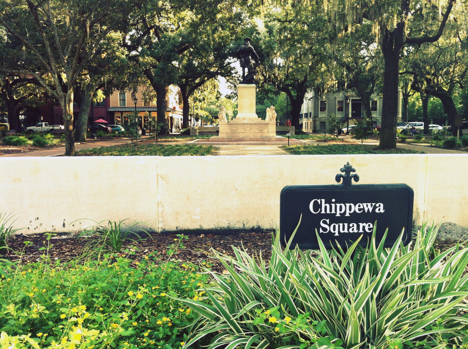 A Savannah historic square with live oaks and Spanish moss where families picnic on parade day