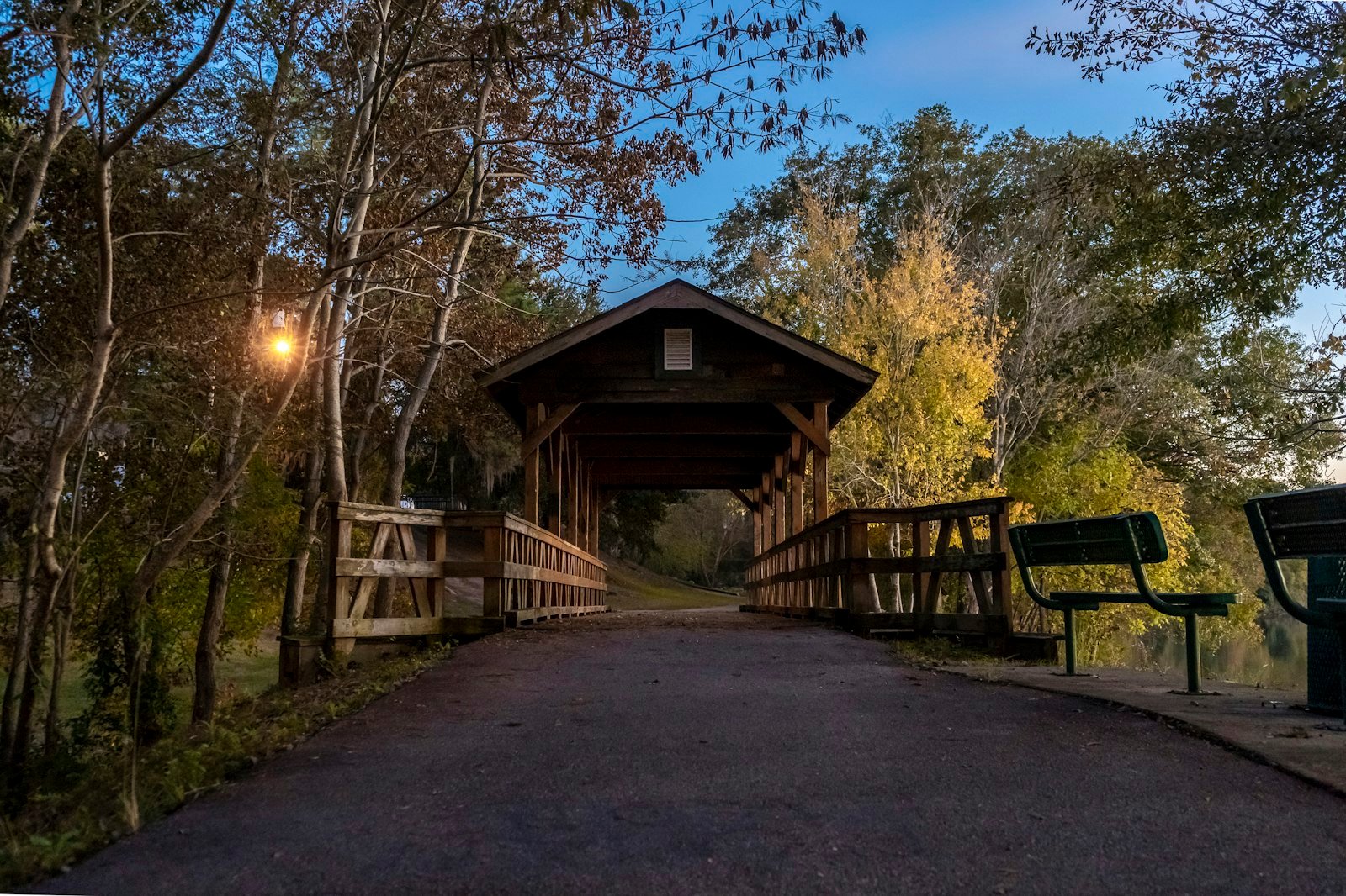 A wooden covered footbridge over the water at dusk in Columbus, Georgia