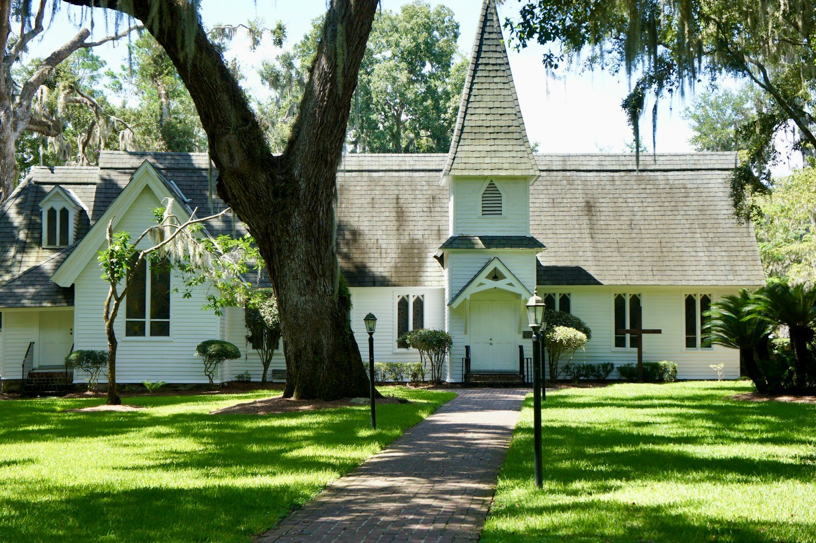 The white Christ Church chapel on St. Simons Island under live oaks with a brick path leading to it