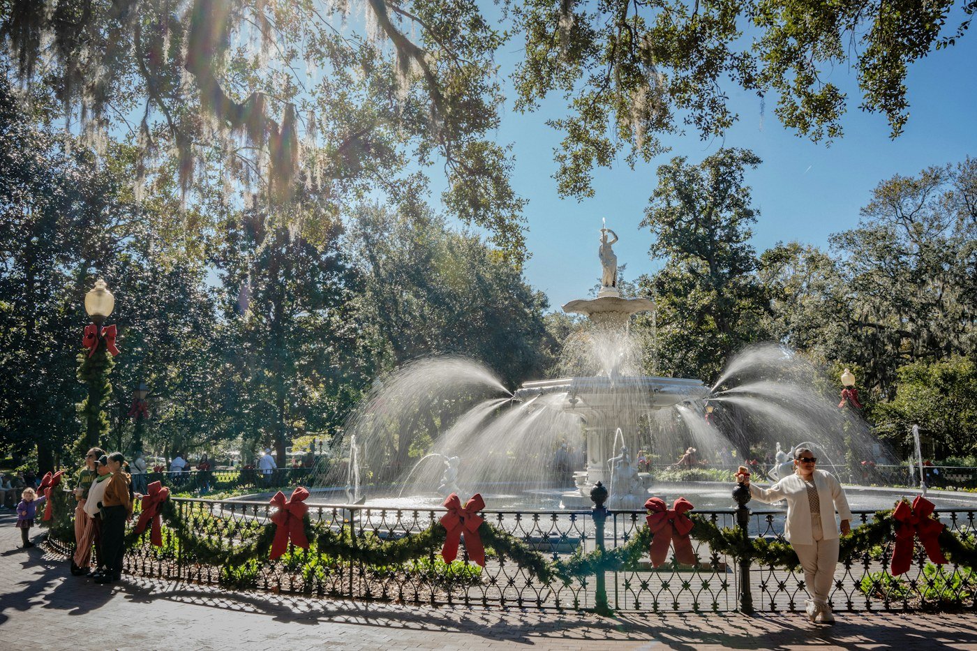 Forsyth Park fountain in Savannah, Georgia, with red Christmas bows and garland on the fence and lamp posts