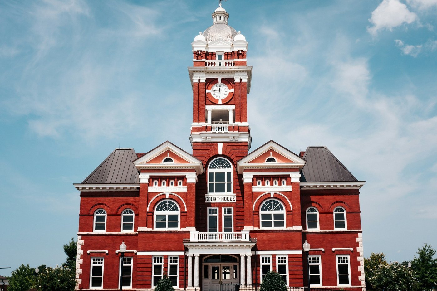 The red brick courthouse with a clock tower and domed cupola in a small Georgia town (Forsyth, per the photographer), under a blue sky.