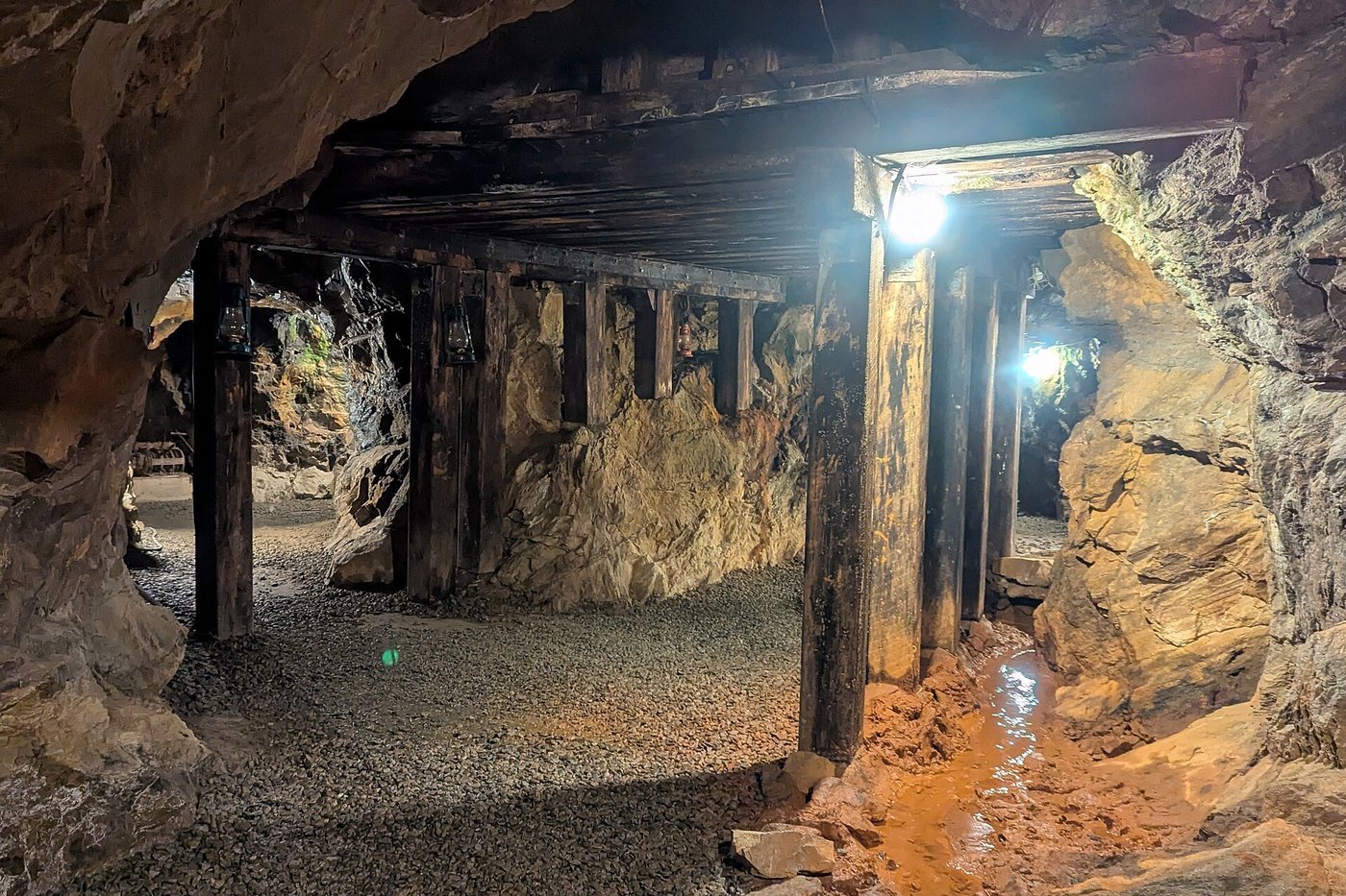 A timber-supported gold mine tunnel with lights and orange rock at Dahlonega, Georgia.