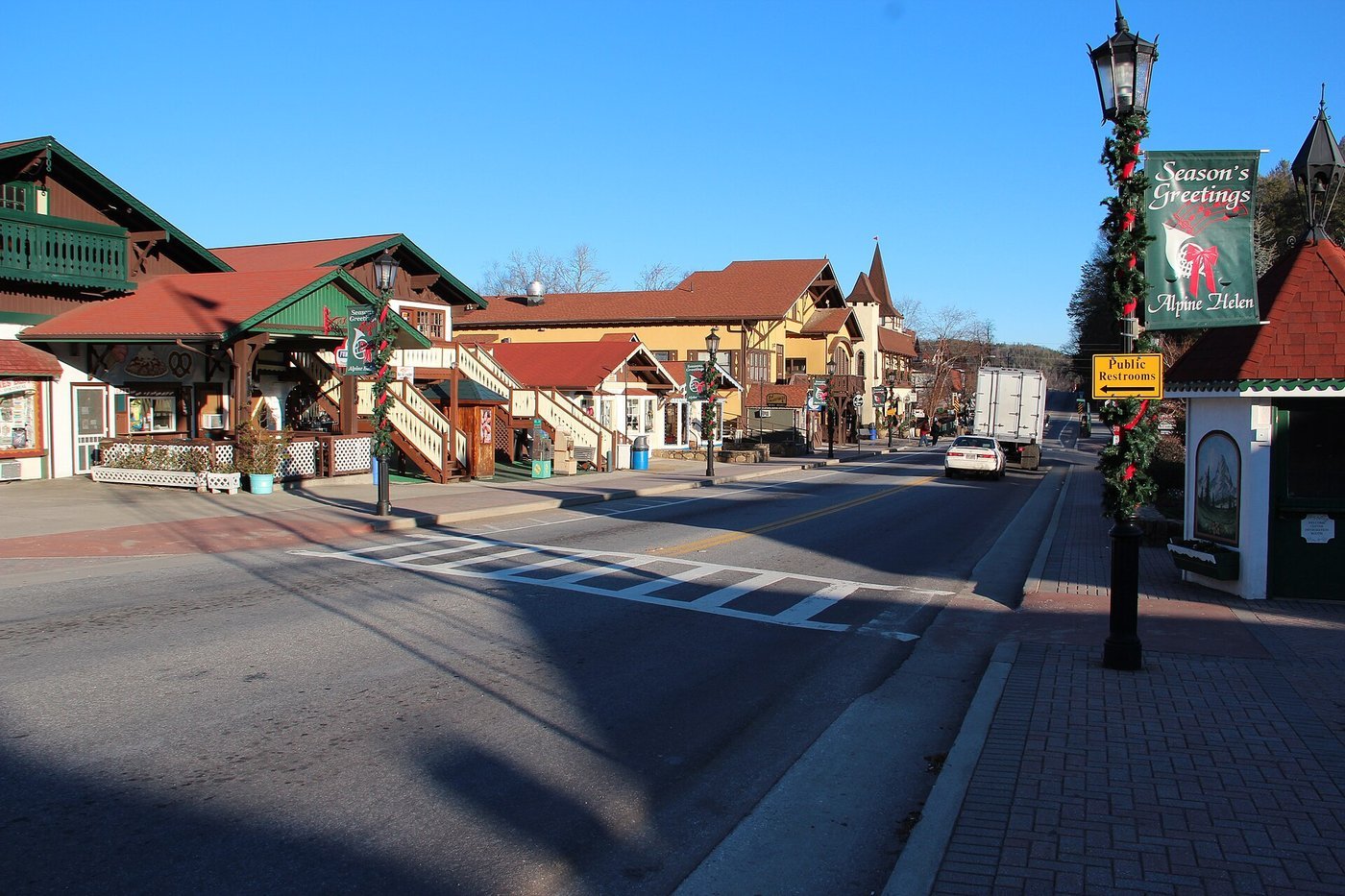 An Alpine-style main street in Helen, Georgia with garland on the lamp posts and a Season's Greetings banner.