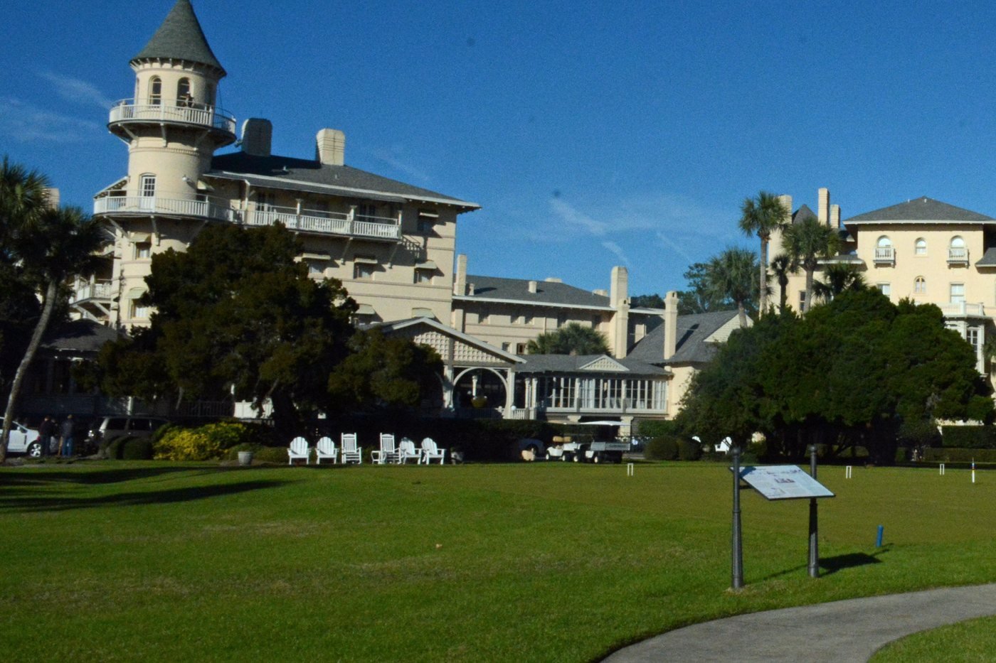 The Jekyll Island Club clubhouse with its round corner turret, seen across the croquet lawn under a blue sky