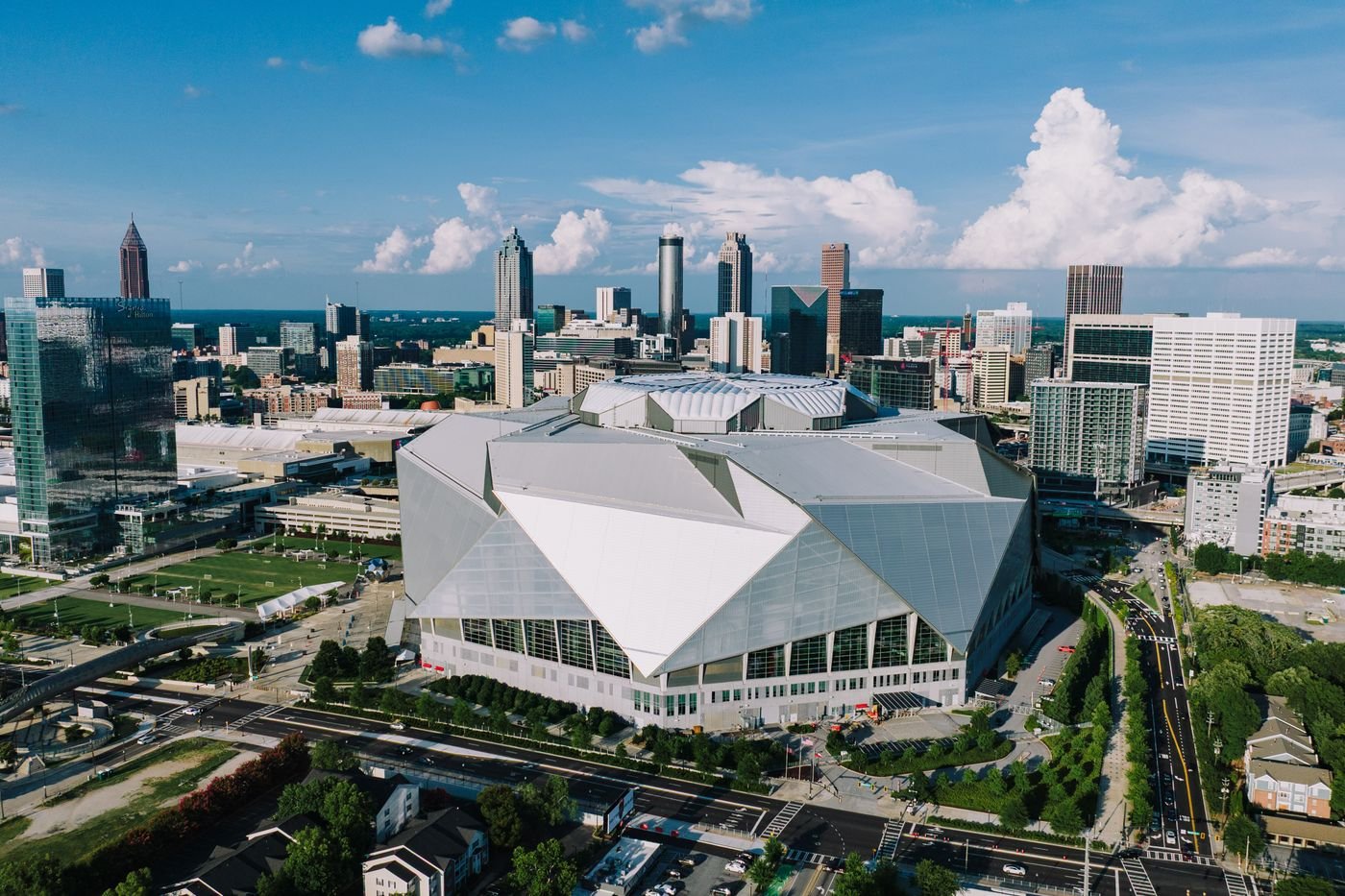 Aerial view of Mercedes-Benz Stadium with the downtown Atlanta skyline behind it