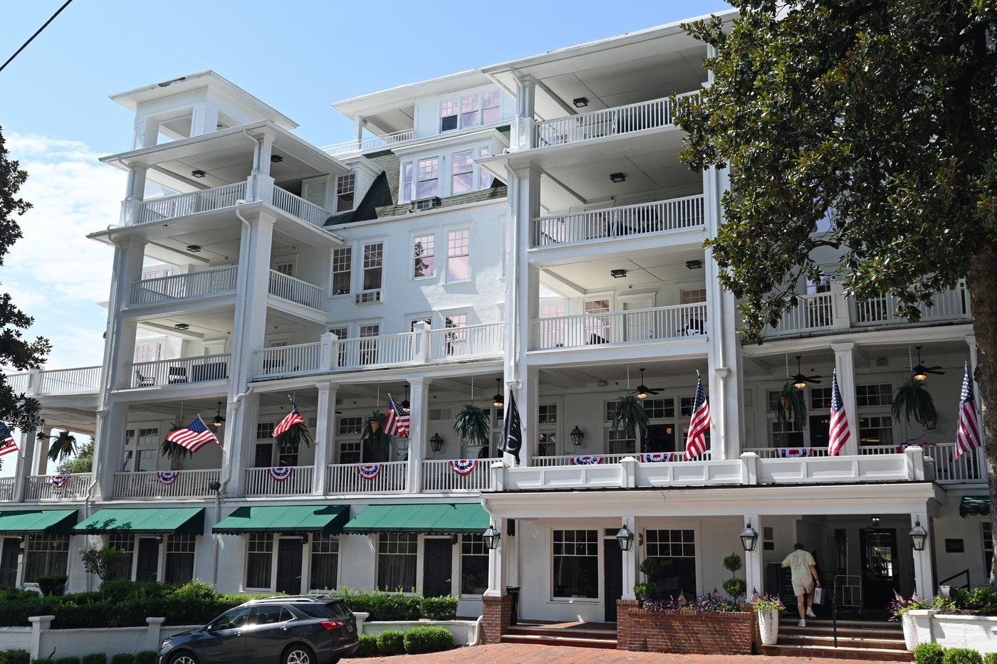 The white Partridge Inn in Augusta with tiers of verandas and balconies, flags along the porch rail and a green-awninged ground floor