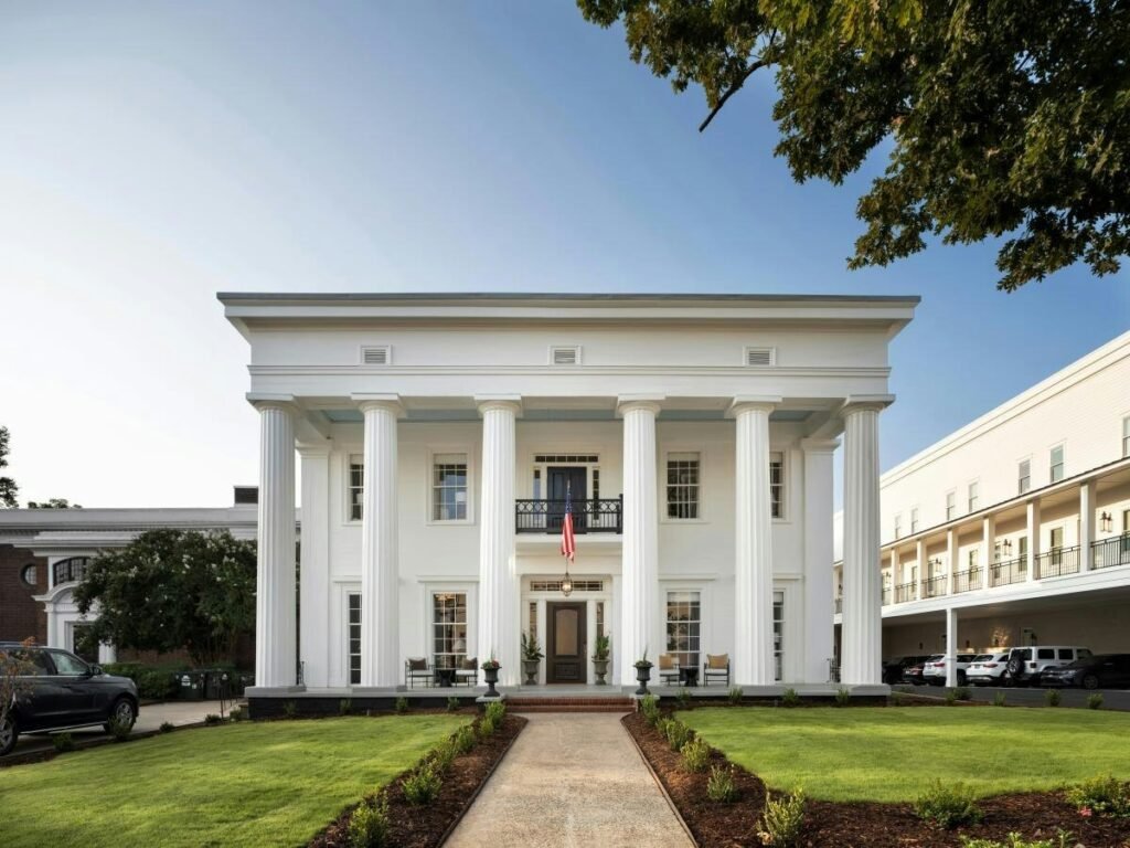 The Athenian’s white Greek Revival mansion in downtown Athens, with six tall columns, a front balcony and a lawn